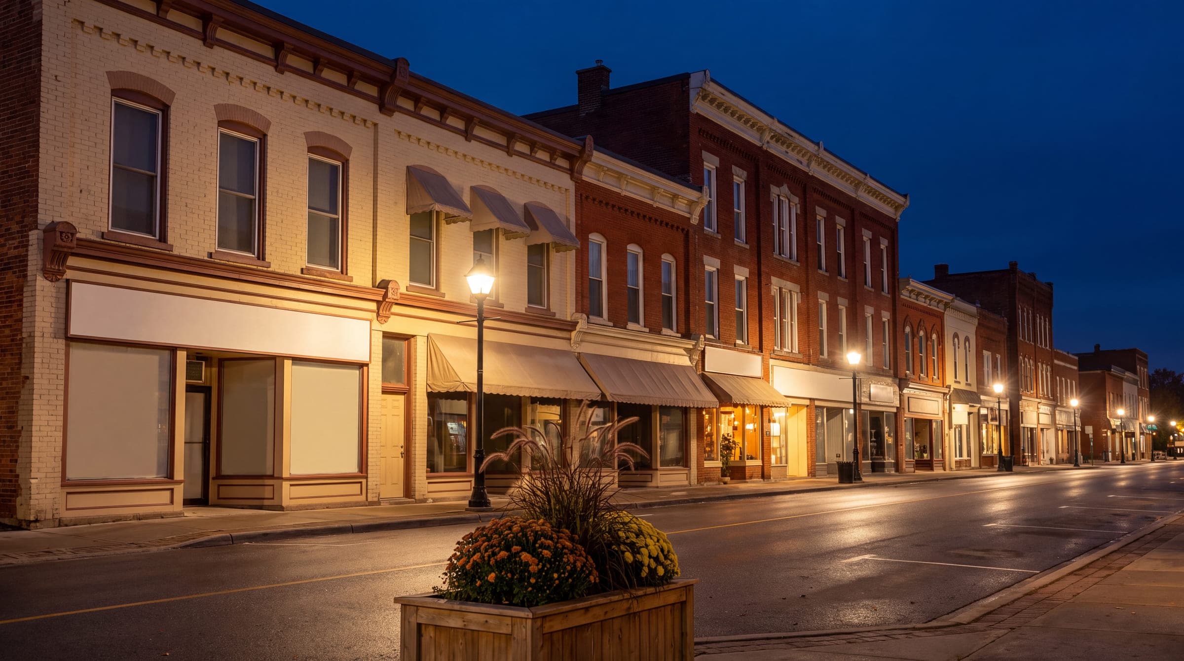 Brick storefronts on a small-town main street lit at blue hour