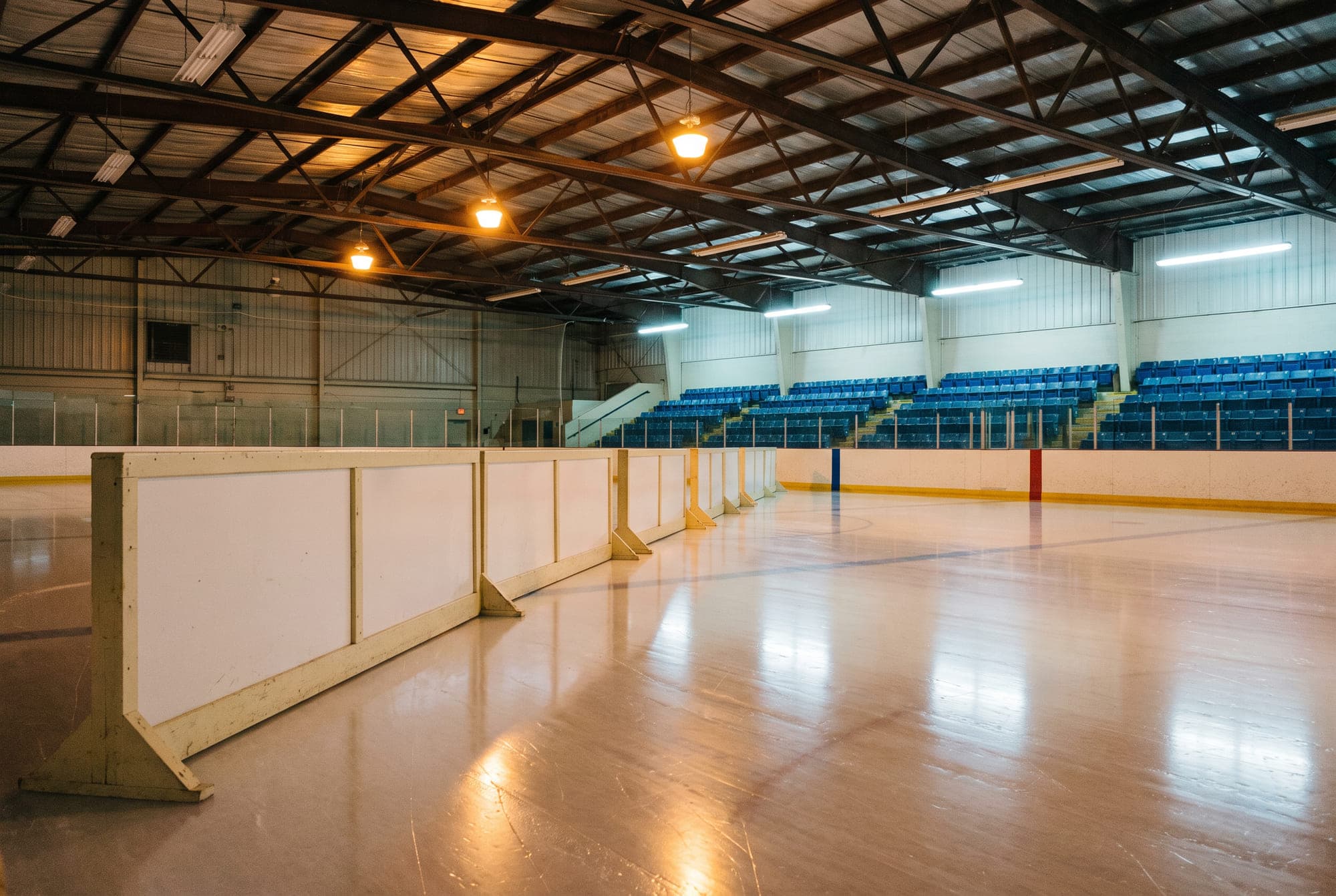 The interior of a small municipal ice arena photographed empty after a fresh resurfacing