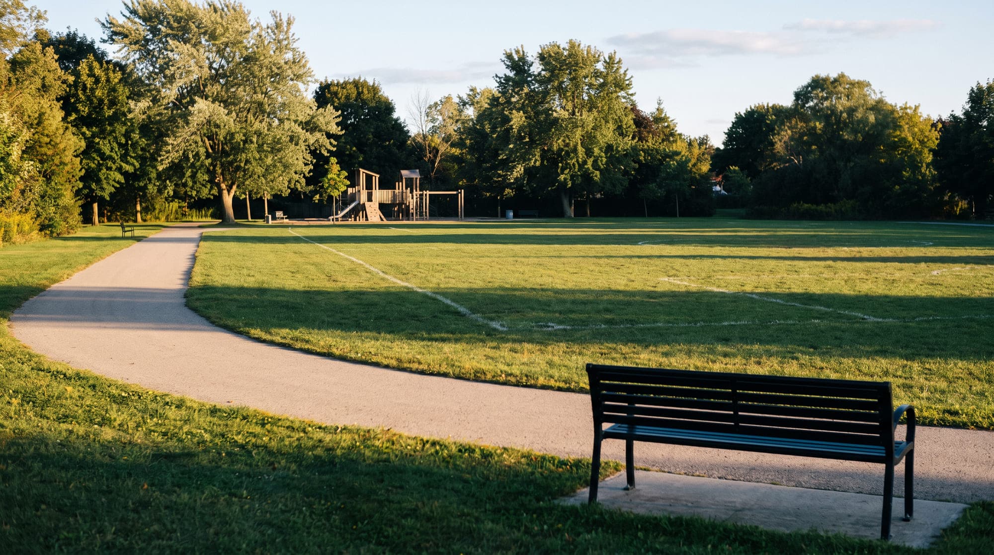 An empty community park with a curving path and a play structure
